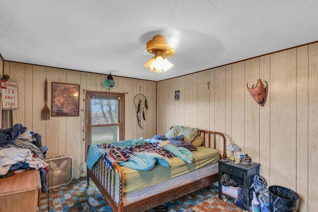 bedroom with a textured ceiling, ceiling fan, and wood walls