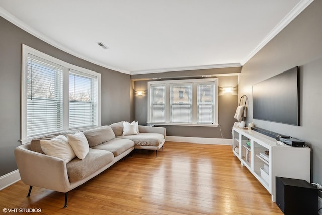 living room with crown molding, light wood-type flooring, visible vents, and baseboards