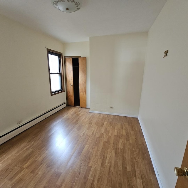 spare room with a baseboard heating unit and light wood-type flooring