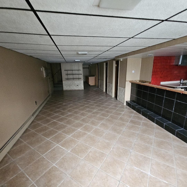 basement with a paneled ceiling and tile patterned flooring