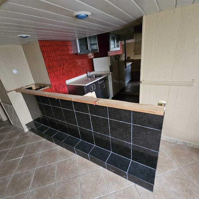 kitchen with tile patterned floors, white refrigerator, kitchen peninsula, and sink