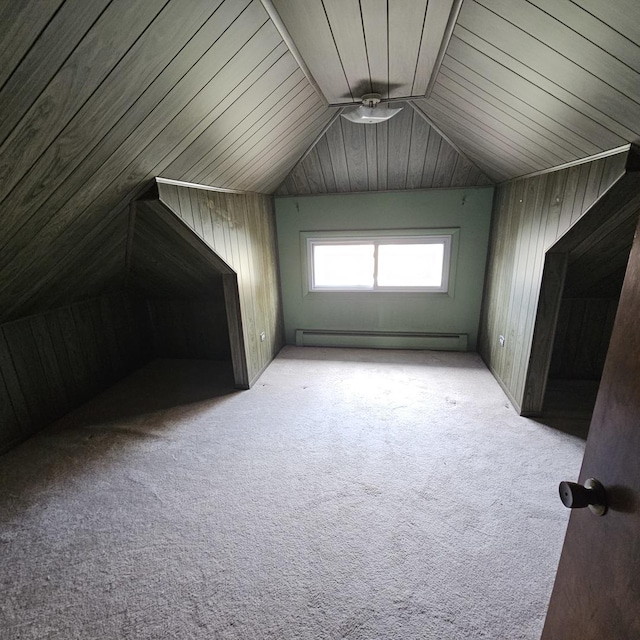 additional living space featuring light carpet, baseboard heating, lofted ceiling, and wood walls