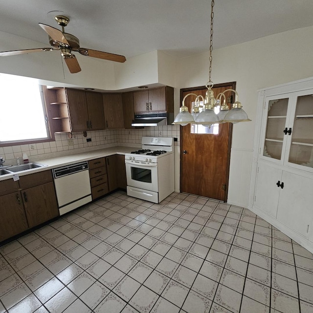 kitchen featuring dark brown cabinetry, backsplash, decorative light fixtures, white appliances, and ceiling fan with notable chandelier