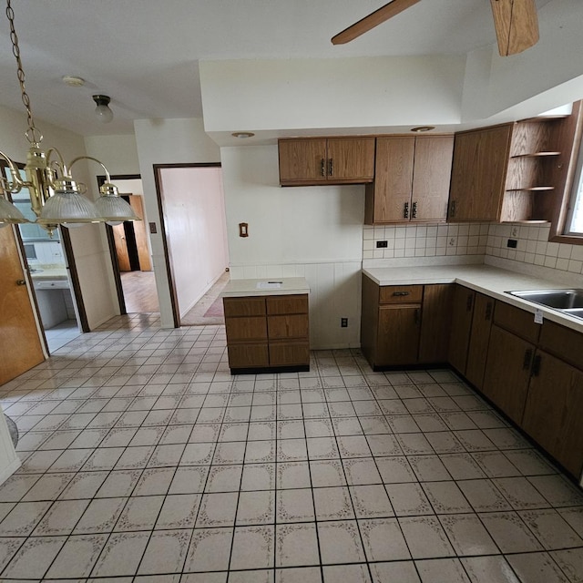 kitchen with pendant lighting, backsplash, ceiling fan, and sink