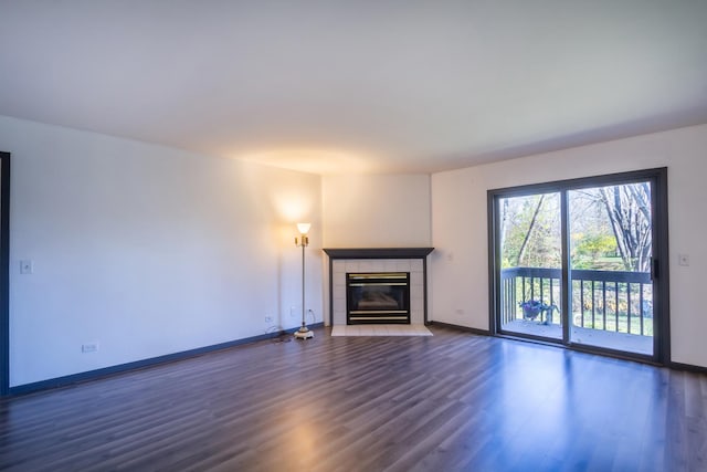 unfurnished living room with a tiled fireplace and dark wood-type flooring