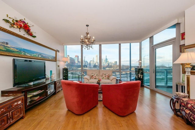 living room featuring light hardwood / wood-style floors, a wall of windows, and an inviting chandelier