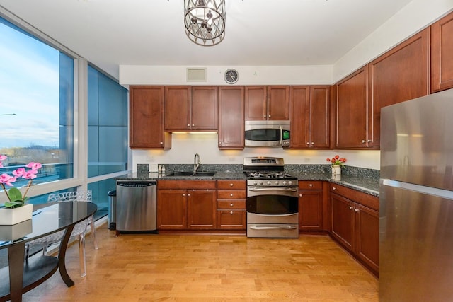 kitchen featuring light hardwood / wood-style floors, sink, stainless steel appliances, and dark stone counters