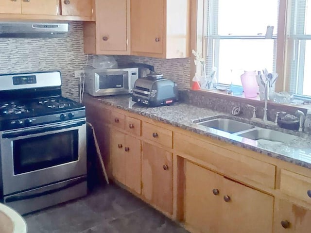 kitchen with sink, stainless steel gas range, tasteful backsplash, light stone counters, and extractor fan