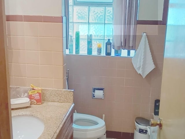 bathroom featuring vanity, tile walls, and toilet