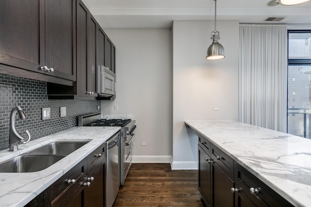 kitchen with light stone countertops, sink, hanging light fixtures, dark hardwood / wood-style floors, and appliances with stainless steel finishes