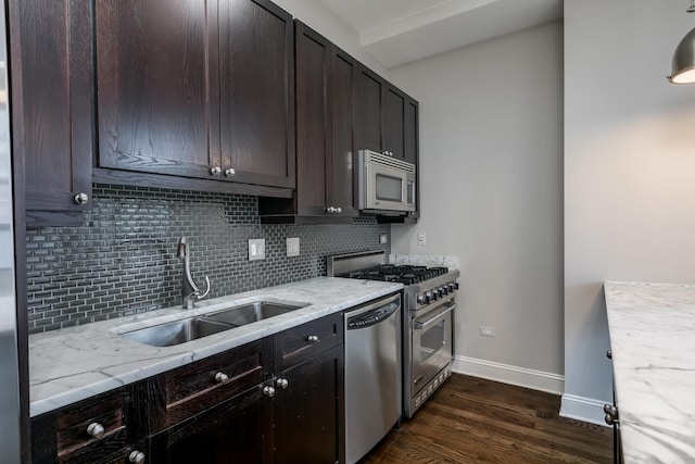 kitchen with appliances with stainless steel finishes, tasteful backsplash, light stone counters, sink, and dark hardwood / wood-style floors