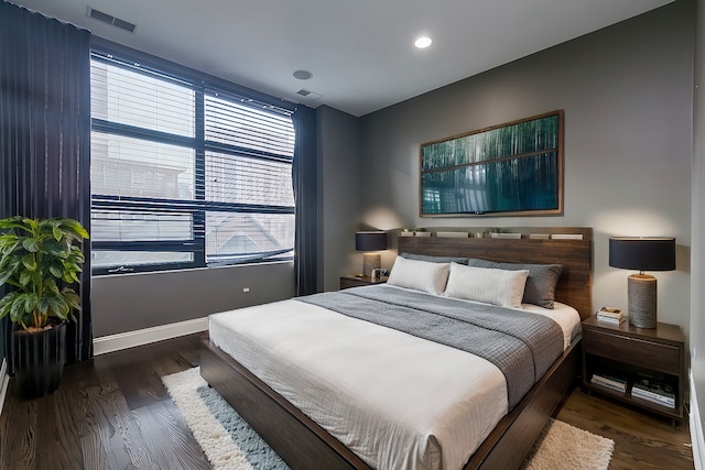 bedroom with dark hardwood / wood-style floors and multiple windows