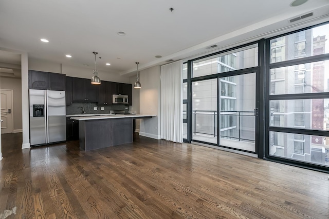 kitchen with backsplash, hanging light fixtures, dark wood-type flooring, and appliances with stainless steel finishes