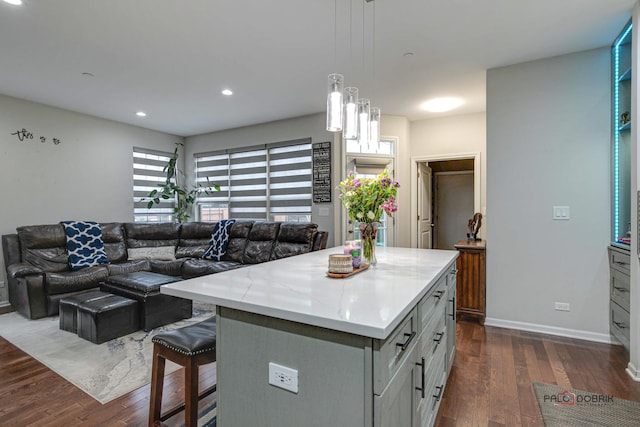 kitchen featuring a breakfast bar, pendant lighting, a center island, and dark wood-type flooring