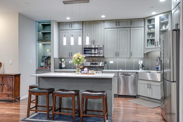 kitchen featuring pendant lighting, hardwood / wood-style floors, sink, gray cabinets, and appliances with stainless steel finishes