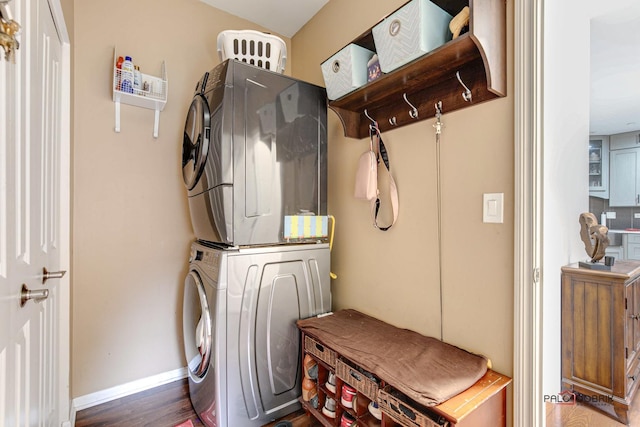 clothes washing area featuring dark hardwood / wood-style flooring and stacked washer and clothes dryer