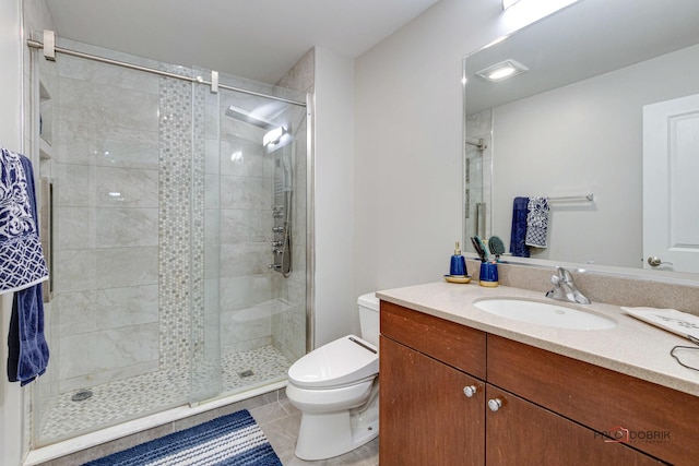 bathroom featuring tile patterned flooring, vanity, toilet, and a shower with door