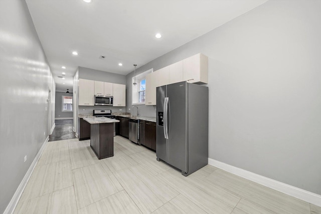 kitchen with pendant lighting, white cabinets, sink, a kitchen island, and stainless steel appliances