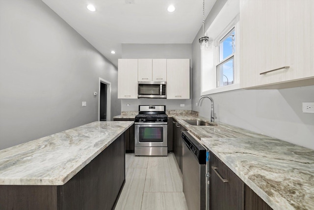 kitchen with sink, dark brown cabinets, light stone counters, white cabinetry, and stainless steel appliances