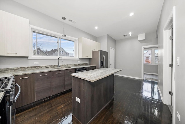 kitchen with sink, stainless steel appliances, dark hardwood / wood-style flooring, dark brown cabinets, and a kitchen island