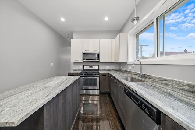 kitchen featuring white cabinetry, sink, light stone counters, dark hardwood / wood-style floors, and appliances with stainless steel finishes