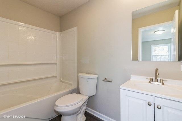 full bathroom with bathing tub / shower combination, vanity, and toilet