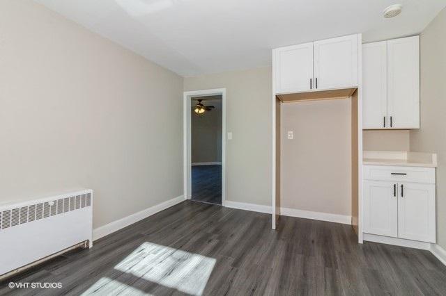 unfurnished bedroom with dark wood-type flooring and radiator