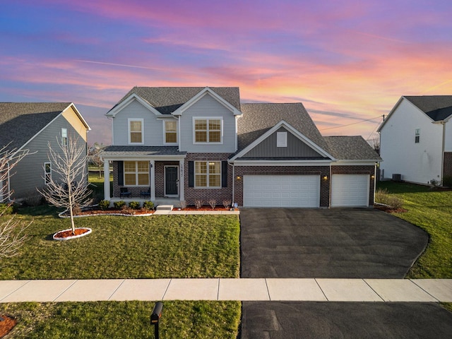 traditional-style home featuring a shingled roof, an attached garage, brick siding, a front lawn, and driveway