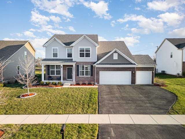 view of front of home featuring roof with shingles, a front yard, brick siding, a garage, and driveway