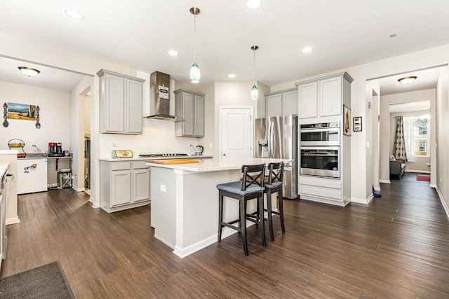 kitchen featuring gray cabinets, dark wood-style floors, wall chimney exhaust hood, and stainless steel appliances