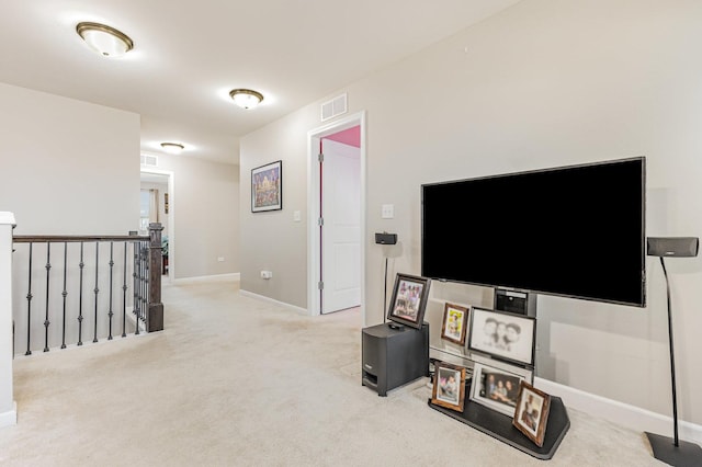 interior space with an upstairs landing, visible vents, light colored carpet, and baseboards