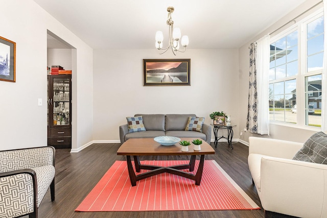 living area with a wealth of natural light, a notable chandelier, and wood finished floors