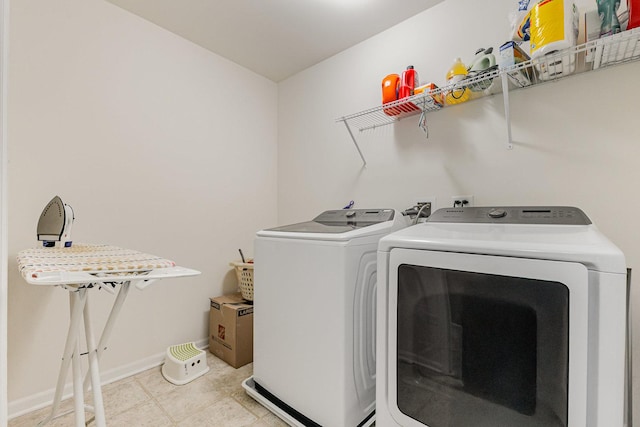clothes washing area with independent washer and dryer, laundry area, and baseboards