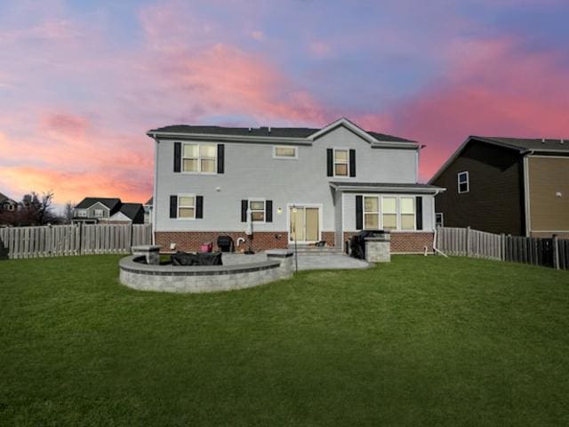 back of house with a yard, a fenced backyard, brick siding, and a patio area