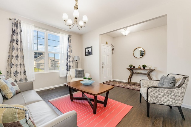 living room featuring visible vents, baseboards, an inviting chandelier, and wood finished floors