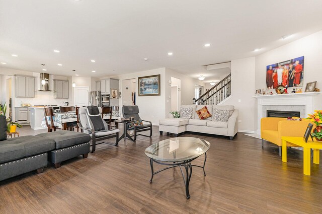 living area featuring baseboards, a fireplace, recessed lighting, stairs, and dark wood-type flooring