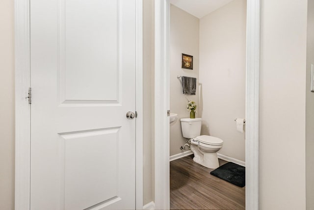 bathroom with toilet, wood finished floors, and baseboards