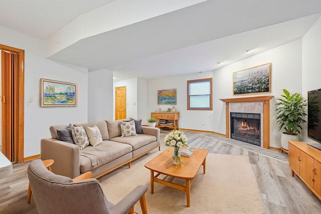 living room featuring light wood-type flooring and a tiled fireplace