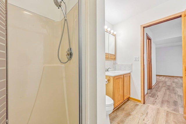 bathroom featuring toilet, vanity, wood-type flooring, and walk in shower