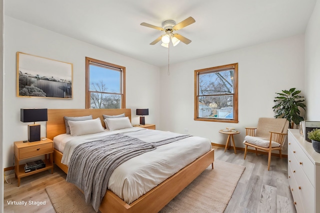 bedroom featuring ceiling fan, light hardwood / wood-style flooring, and multiple windows