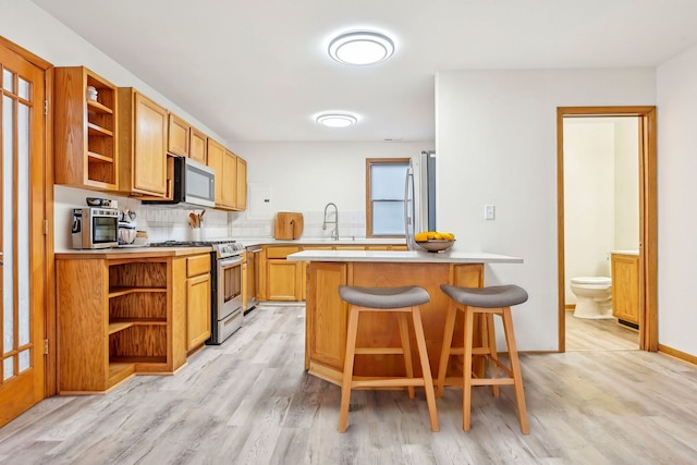 kitchen featuring stainless steel appliances, tasteful backsplash, light hardwood / wood-style floors, a breakfast bar area, and a kitchen island