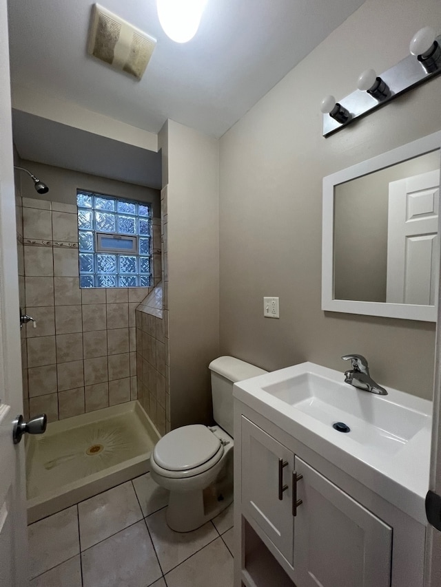 bathroom with toilet, a tile shower, vanity, and tile patterned floors