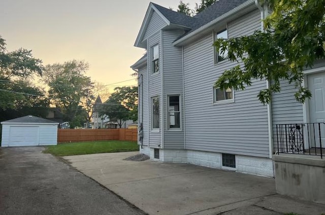 property exterior at dusk featuring an outdoor structure and a yard