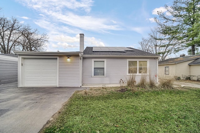 single story home featuring a garage, a front yard, and solar panels