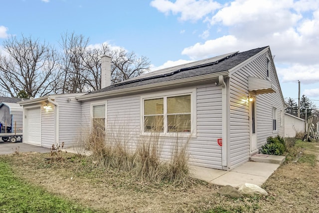 view of side of property with solar panels and a garage