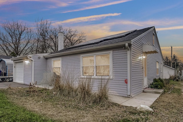 property exterior at dusk with solar panels and a garage