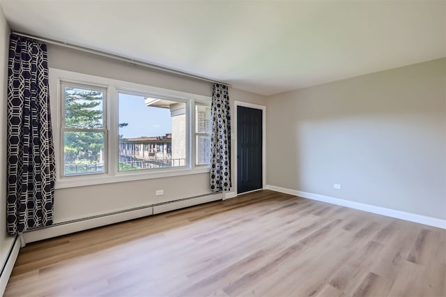 spare room featuring a baseboard radiator and light hardwood / wood-style flooring