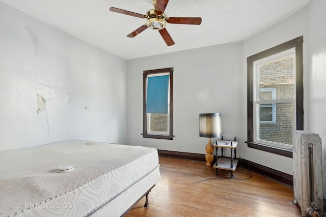 bedroom with hardwood / wood-style flooring, ceiling fan, and radiator