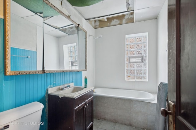 bathroom featuring tile patterned floors, vanity, toilet, and tiled bath