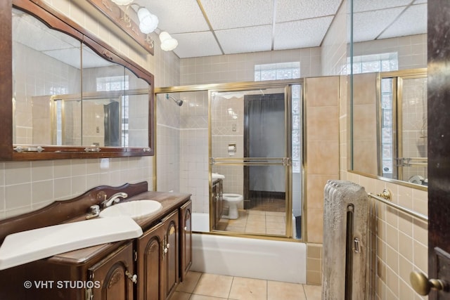 full bathroom featuring decorative backsplash, bath / shower combo with glass door, vanity, tile walls, and tile patterned flooring